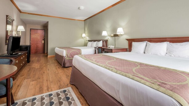 A hotel room with two beds, a desk with a television, and a small rug. - Super 8 by Wyndham Grayson (Grayson)