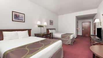 A hotel room with two beds, a desk, a chair, a TV, and a door leading to another room.