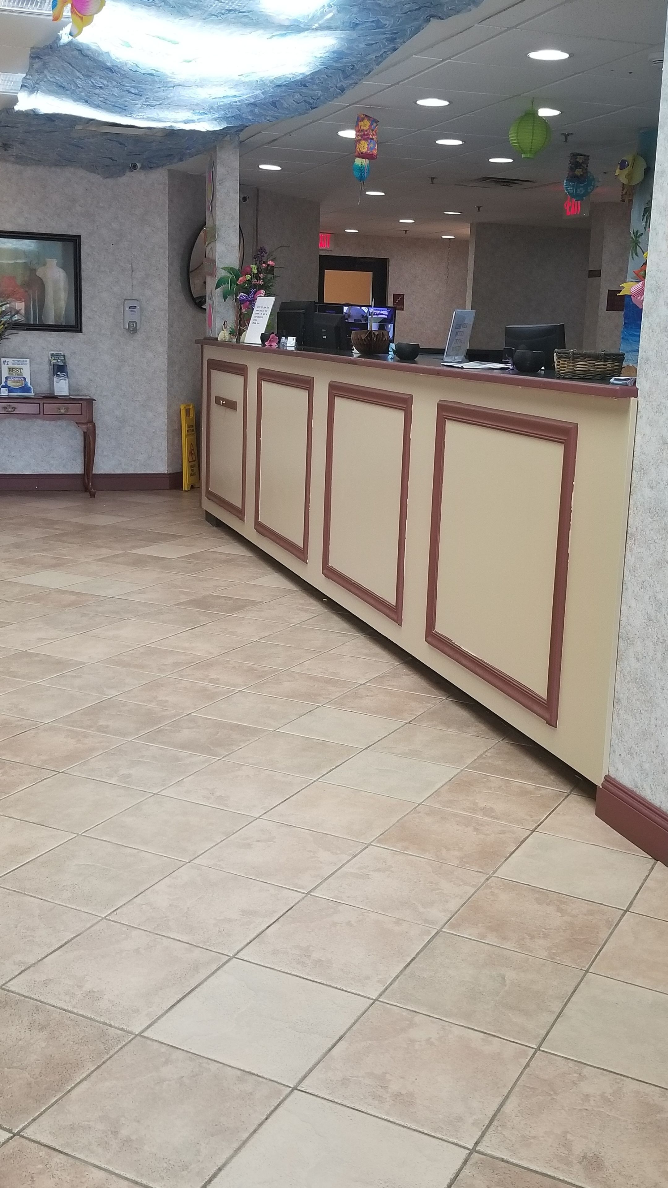 Un'area di accoglienza con pavimento piastrellato, una scrivania della reception, un computer e una sveglia a parete.
