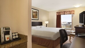 Una habitación de hotel con cama, escritorio, silla, cafetera y televisor.