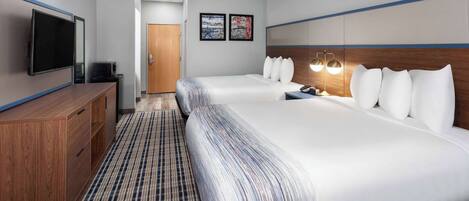 A hotel room with two beds, a TV, a desk, and a door.