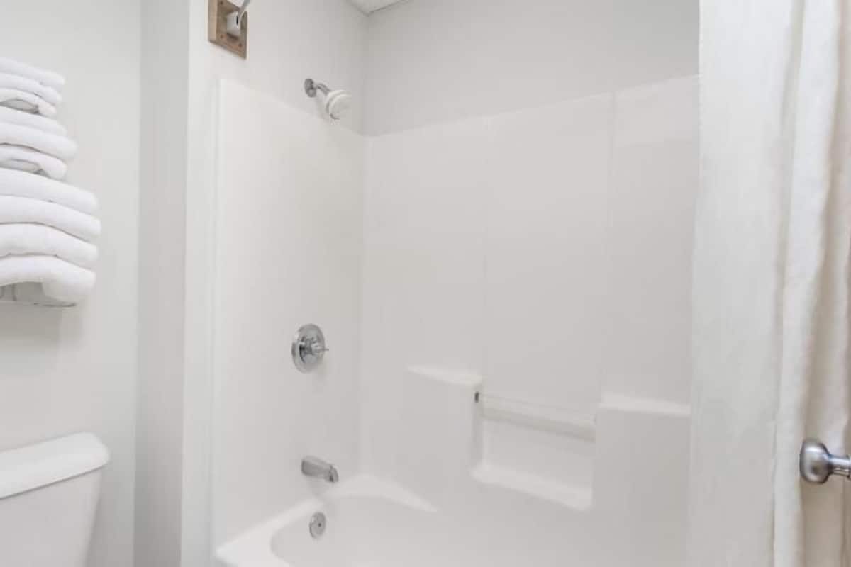 Een douche met glazen deur, een toilet en een handdoekrek met opgevouwen handdoeken.