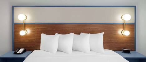 A hotel room with a wooden headboard, white bedding, and bedside lamps.