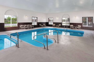 Una piscina con barandillas de metal, paredes blancas y ventanas amplias.