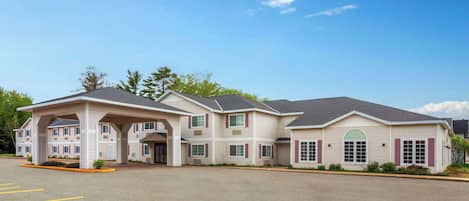 A multi-story hotel with a covered entrance and a parking lot.