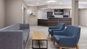 A reception area with a reception desk, a blue sofa, a wooden coffee table, and a blue armchair. - AmericInn by Wyndham Eagle River Downtown (Eagle River)