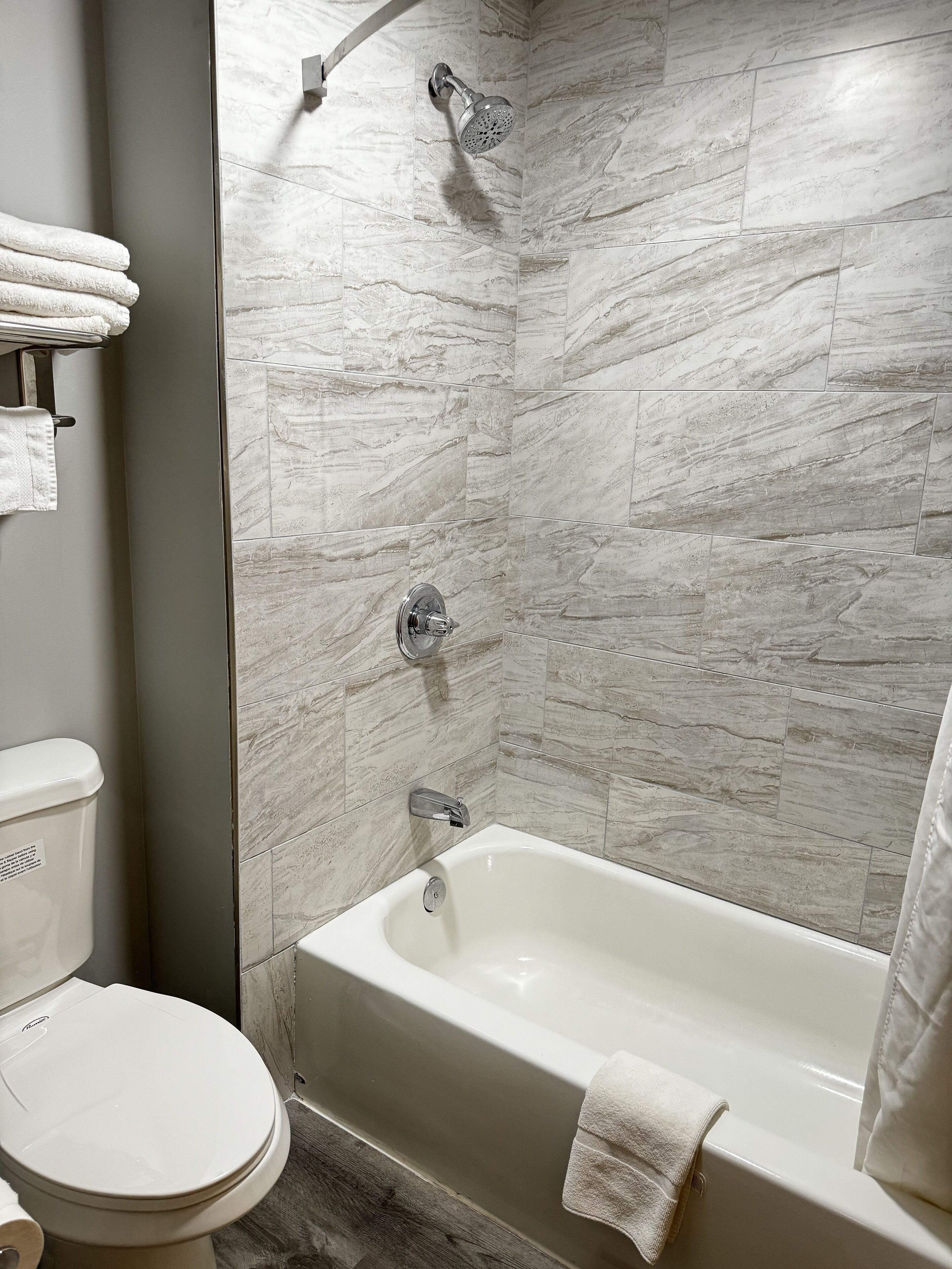 A bathroom with a bathtub, a showerhead, and a toilet.
