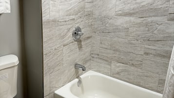 Ein Badezimmer mit Badewanne, Duschkopf und Toilette.