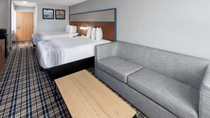 A hotel room with a double bed, a grey sofa, a wooden coffee table, and a checkered floor. - AmericInn by Wyndham Eagle River Downtown (Eagle River)