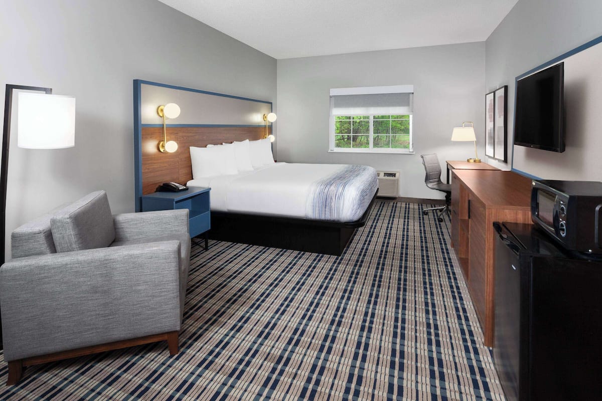Een hotelkamer met een bed, een bureau, een stoel, een televisie en een raam.