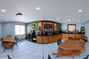 A kitchen with a curved island, wooden cabinets, a window, and a tiled floor. - Coratel Inn & Suites by Jasper Black River Falls (Black River Falls)