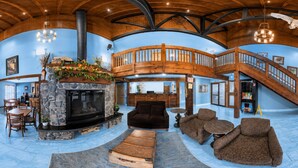 A spacious interior with a stone fireplace, wooden staircase, and a cozy seating area.