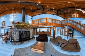 A spacious interior with a stone fireplace, wooden staircase, and a cozy seating area. - Coratel Inn & Suites by Jasper Black River Falls (Black River Falls)