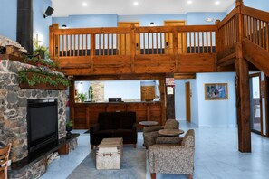 A spacious lobby with a stone fireplace, a wooden staircase, and a reception desk. - Coratel Inn & Suites by Jasper Black River Falls (Black River Falls)