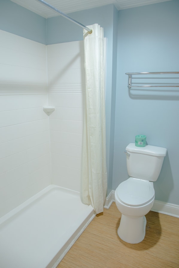 Une salle de bain avec une douche, des toilettes et un porte-serviettes.