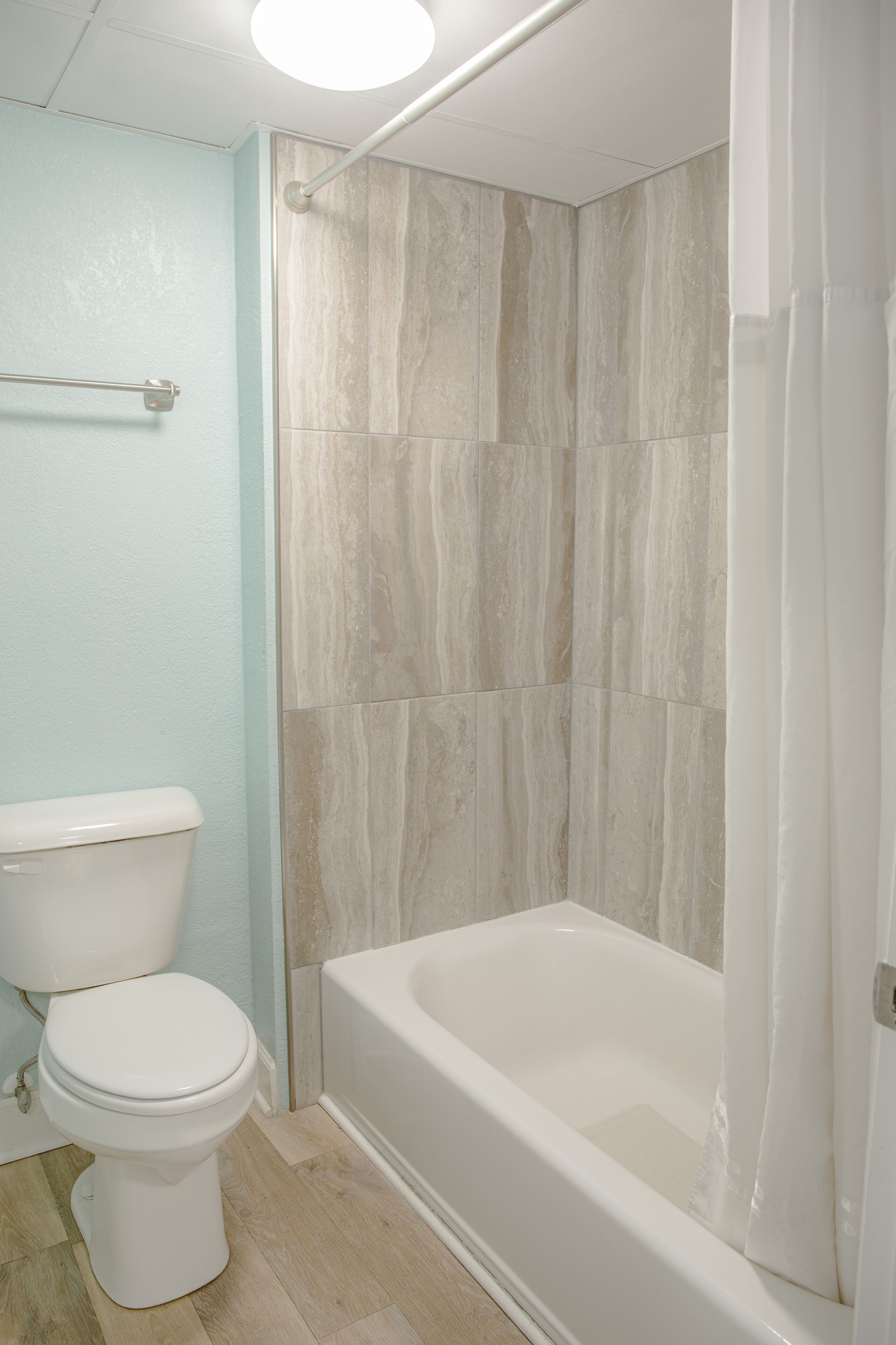 A bathroom with a toilet, a bathtub, and a shower area with tiled walls.