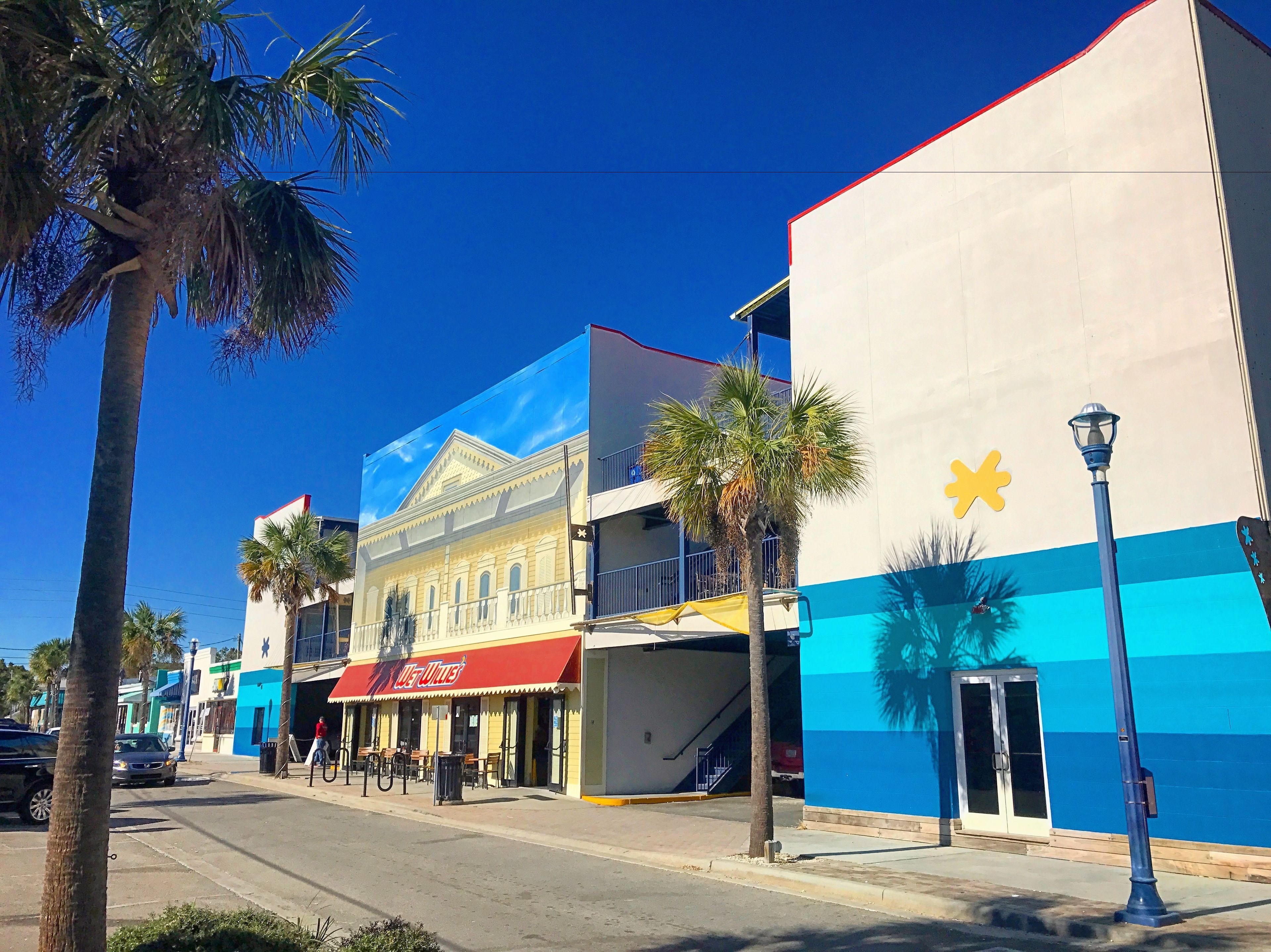 A street view with a building featuring a red awning and a blue and white facade.