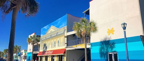 A street view with a building featuring a red awning and a blue and white facade.