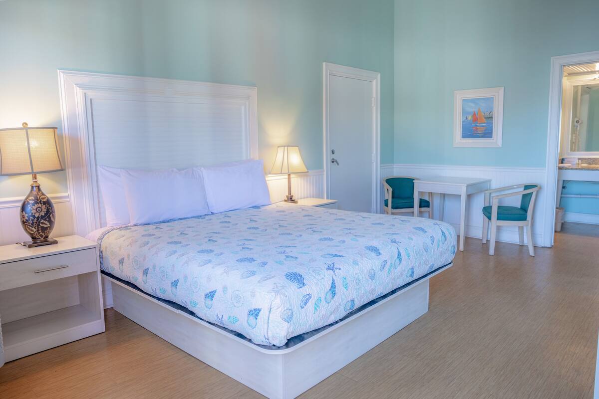 A bedroom with a bed, bedside tables, a desk, and a chair.