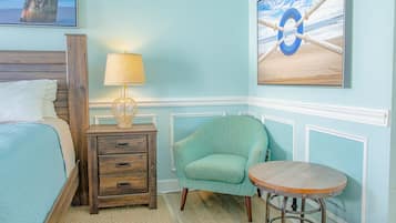 A bedroom with a bed, a nightstand with a lamp, a chair, and a small table.