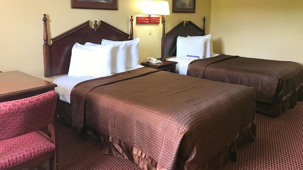 A hotel room with two beds, a desk, a chair, and two paintings on the wall. - Americas Best Value Inn & Suites Maumelle North Little Rock (Maumelle)