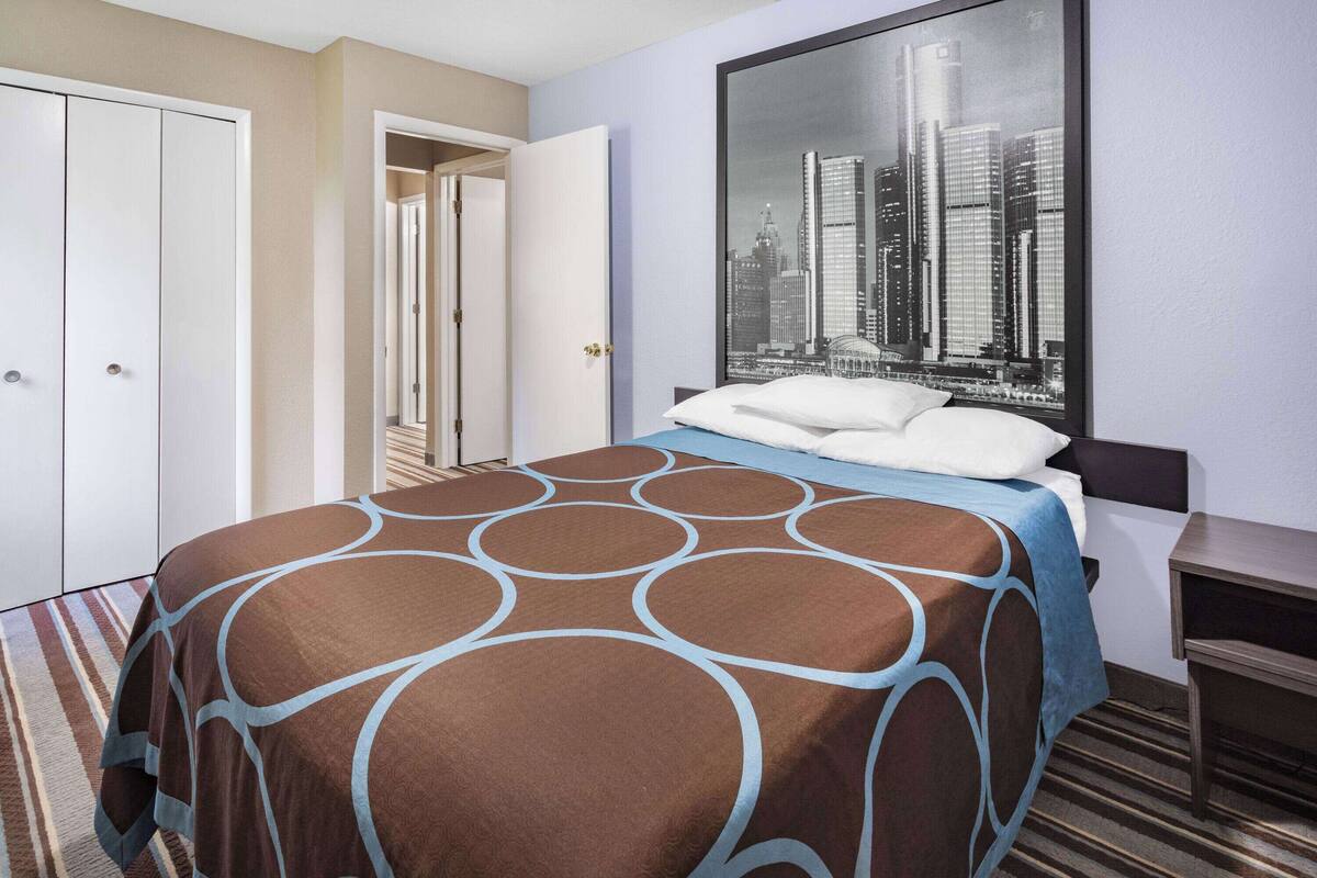 Habitación de hotel con cama, vista panorámica de la ciudad, armario y escritorio.