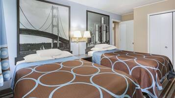 Une chambre d’hôtel avec deux lits, un grand miroir reflétant la vue sur la ville, une table de chevet avec une lampe et une porte sur le côté droit.