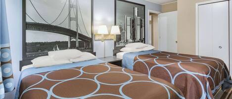 A hotel room with two beds, a large cityscape mirror, a nightstand with a lamp, and a door to the right.
