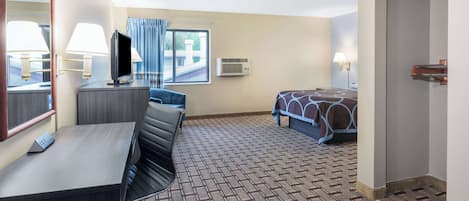Una habitación de hotel con escritorio, cama, televisión y ventana con cortinas.