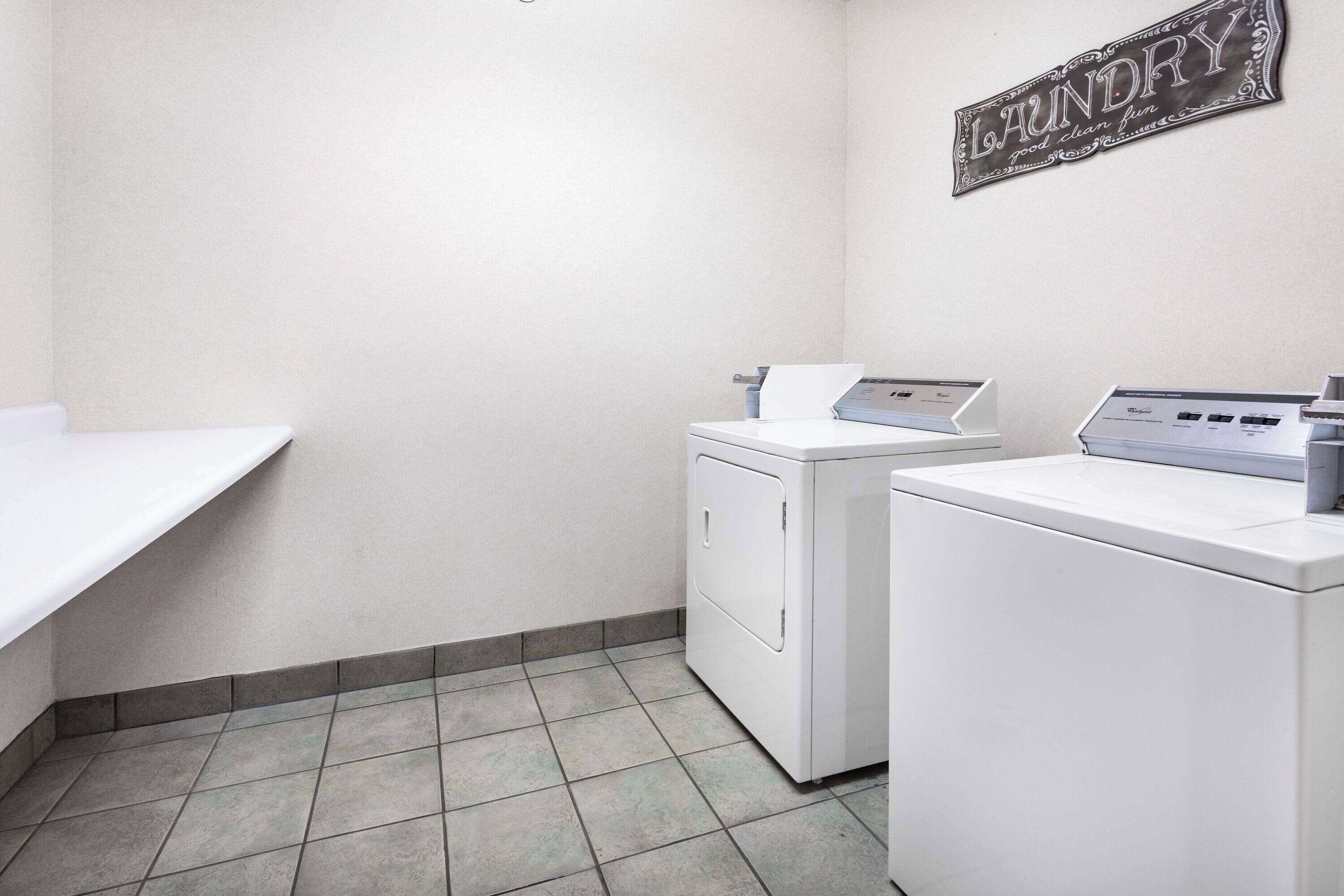 A laundry room with a washing machine, dryer, and a wall-mounted sign that reads "Laundry".