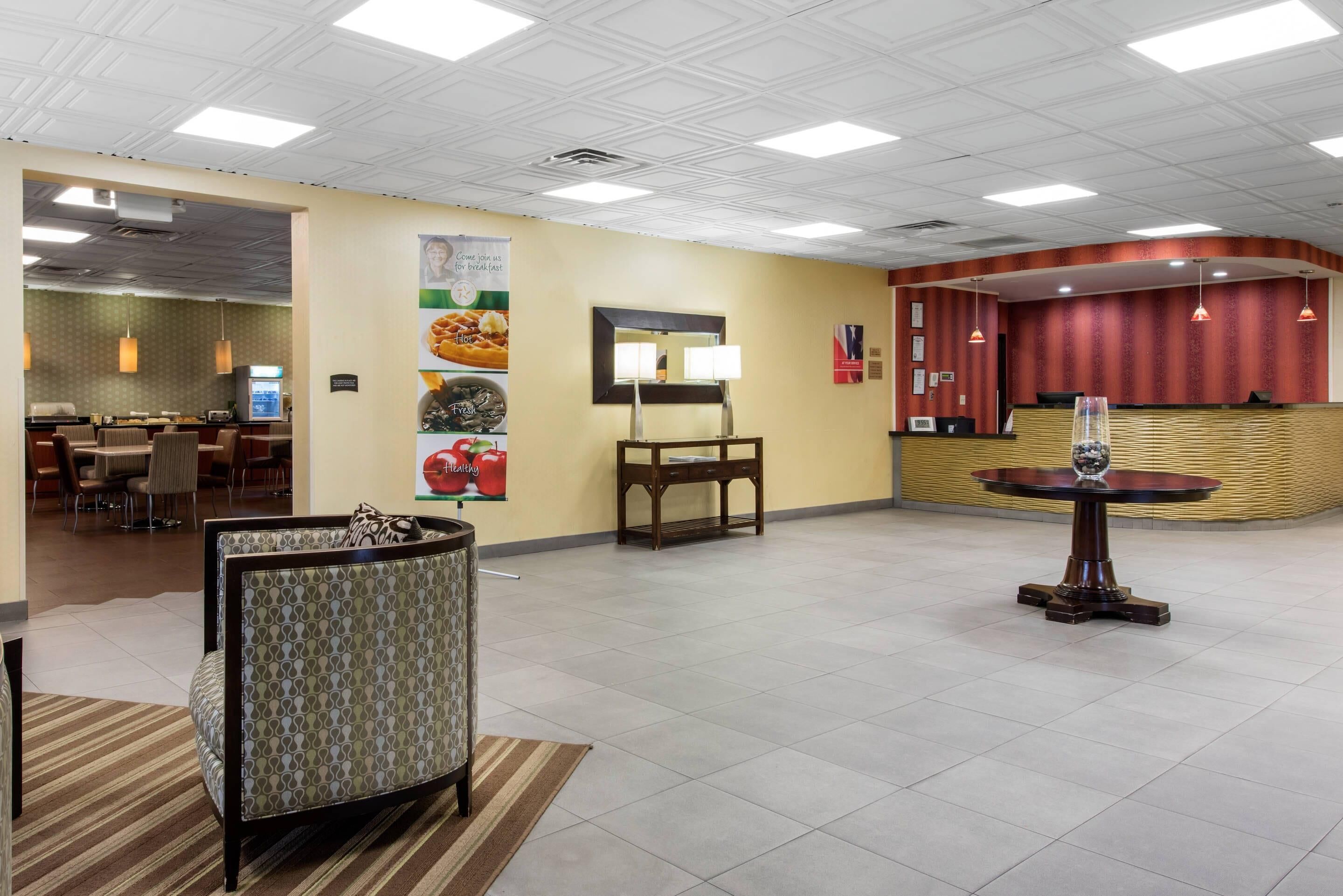 A hotel lobby with a reception desk, seating area, and a dining section.