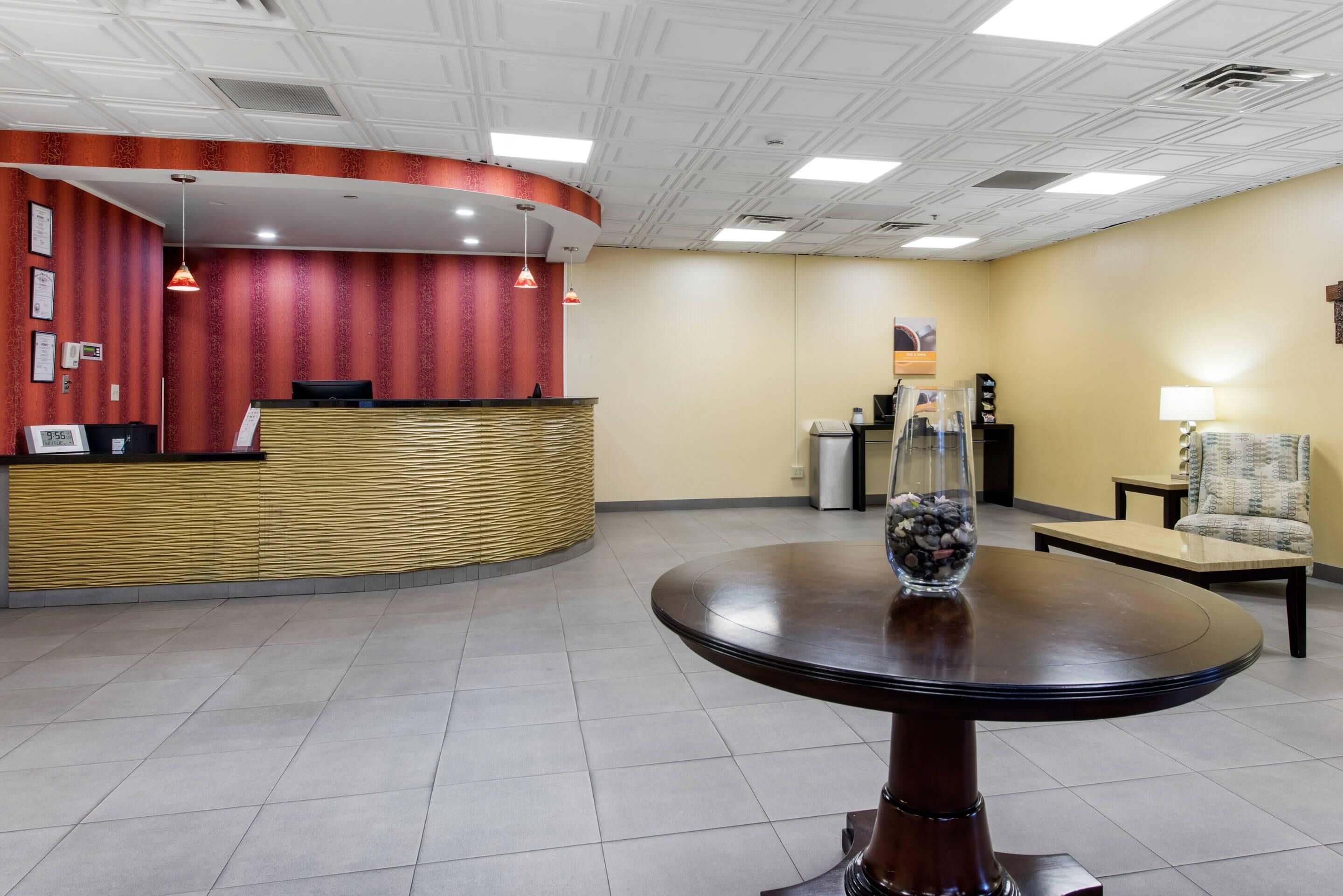A reception area with a curved desk, a round table with a vase, and a chair.