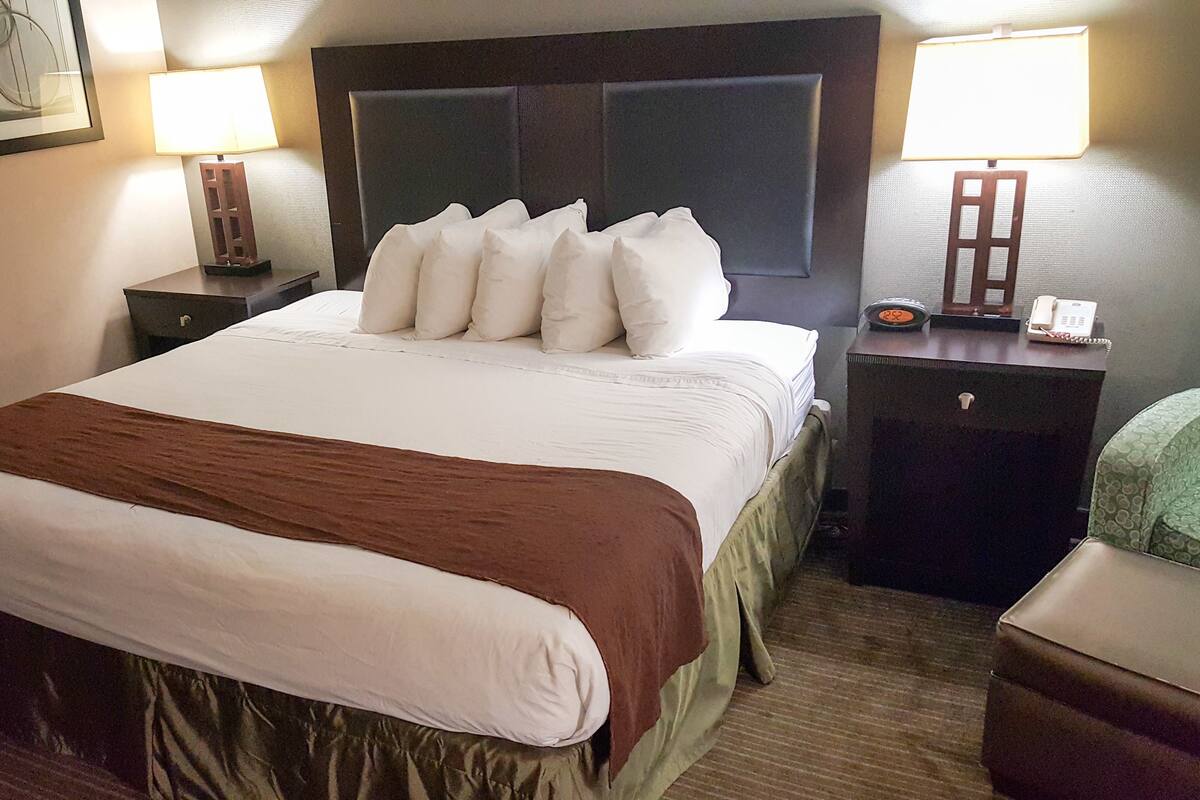 A hotel room with a large bed, two bedside tables, a nightstand, a desk, and a chair.
