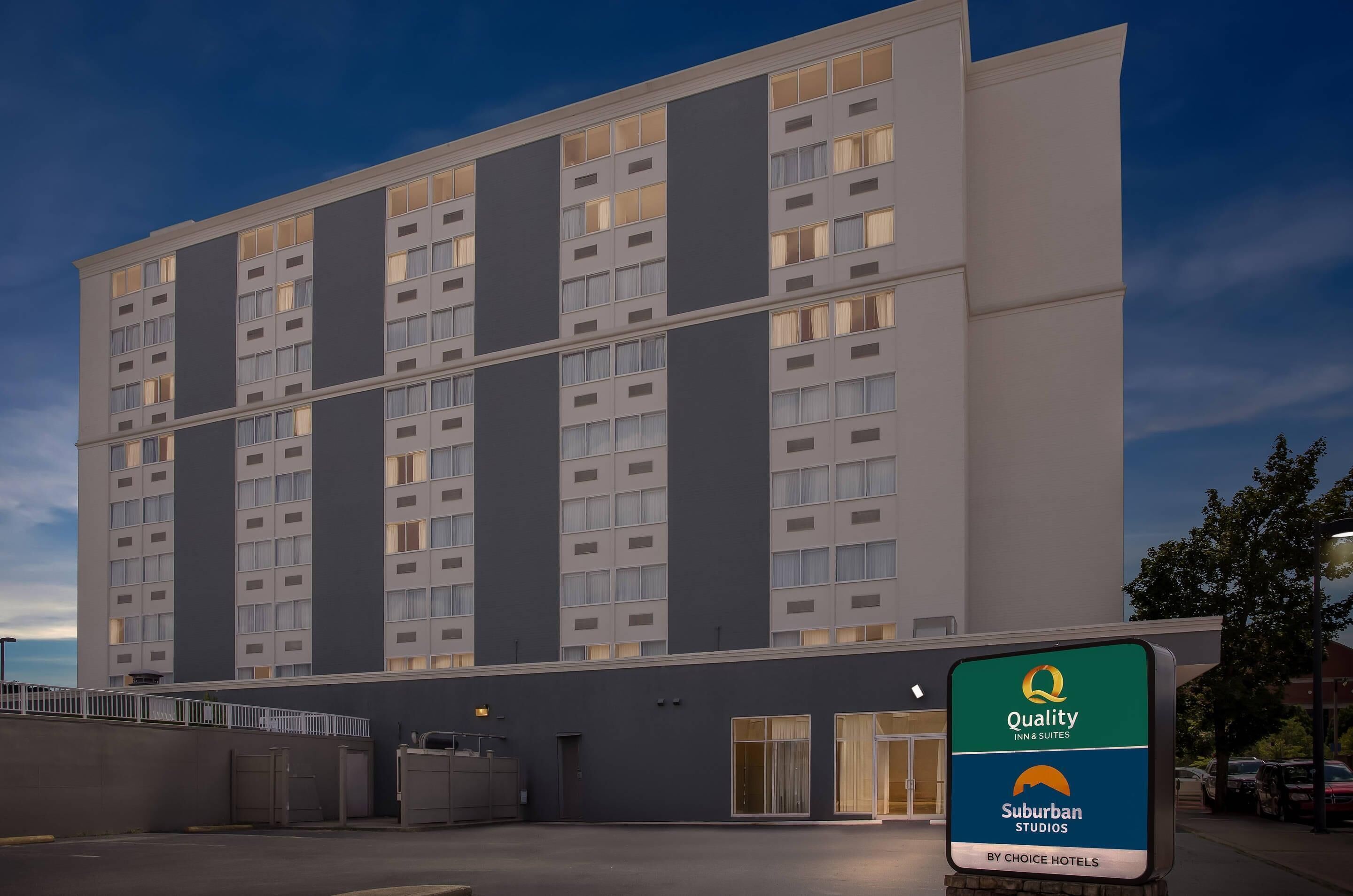 Ein modernes Hotelgebäude mit mehreren Etagen, großen Fenstern und einem Schild, das angibt, dass es sich um ein Quality Inn & Suites by Choice Hotels handelt.