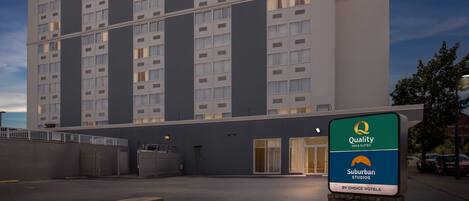 Ein modernes Hotelgebäude mit mehreren Etagen, großen Fenstern und einem Schild, das angibt, dass es sich um ein Quality Inn & Suites by Choice Hotels handelt.