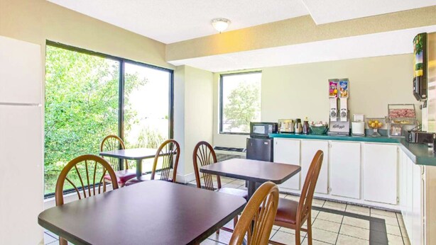 A compact kitchen with a microwave, coffee maker, and small refrigerator. There are two windows providing natural light and a view of greenery outside. - Rodeway Inn Richland - Jackson South (Richland)