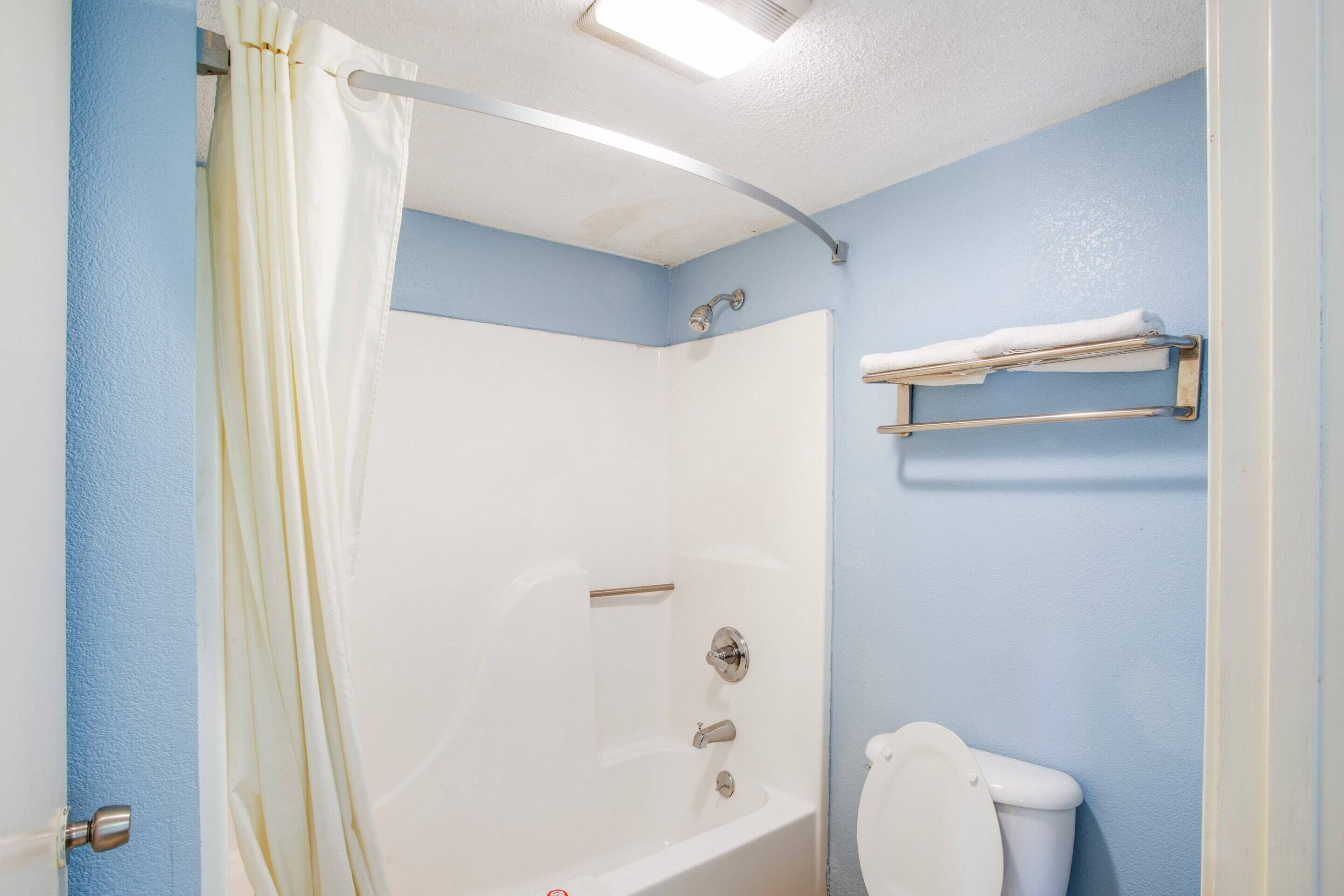 Un baño con bañera, inodoro y toallero.