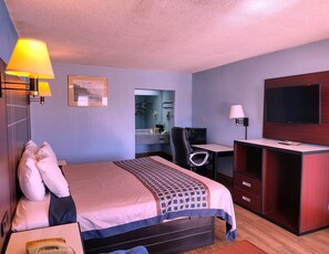 Comfortable room with a neatly made bed, desk, and flat-screen TV.