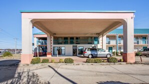 A motel with a covered parking area, multiple balconies, and a car parked in front. - Rodeway Inn Richland - Jackson South (Richland)