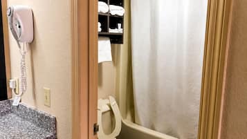 A bathroom with a toilet, a towel rack with towels, a shower curtain, and a hair dryer on the wall.