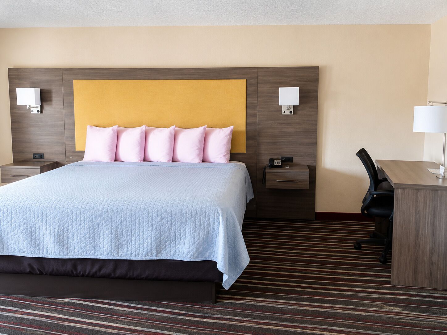 Una habitación de hotel con cama, mesitas de noche, escritorio y una silla.