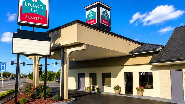 A Legacy Inn building with a covered parking area, a signboard, and a clear sky.