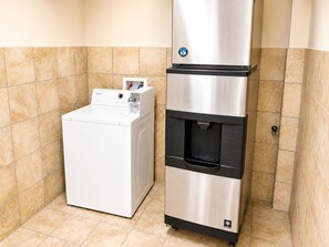 A compact laundry room with a white washing machine and a stainless steel water dispenser. - Legacy Inn Sumner (Gallatin)