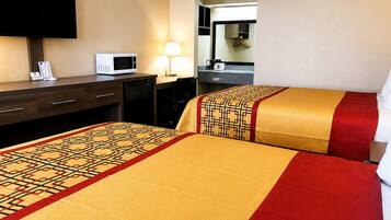A hotel room with two beds, a desk, a television, a microwave, and a lamp.