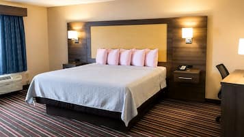 A hotel room with a large bed, bedside lamps, a desk with a telephone, and a window with curtains.