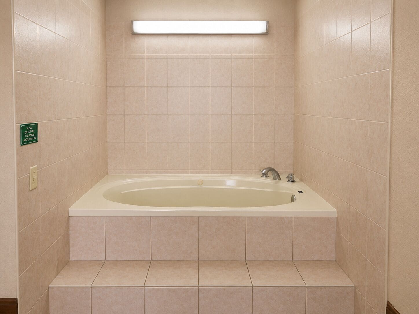 Une salle de bain avec une baignoire, un luminaire au-dessus et un panneau sur le mur.