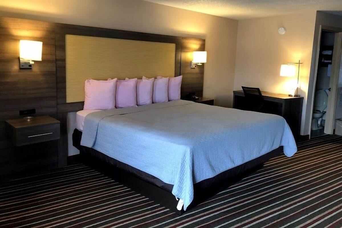 A hotel room with a large bed, two bedside tables, a desk, and a chair.