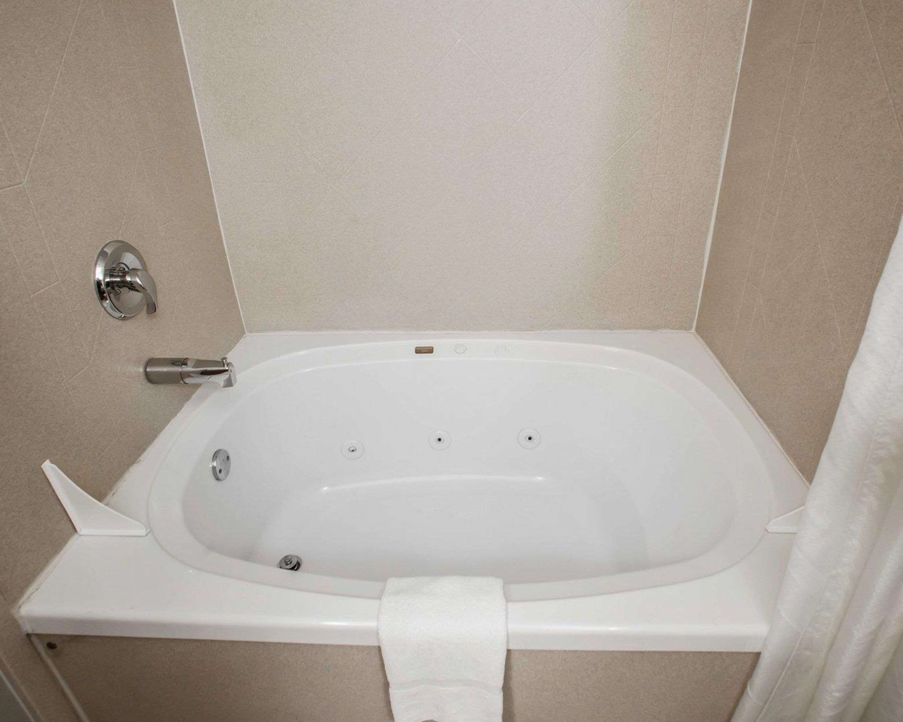 Eine Standardbadewanne mit Duschbedienelement, Handtuchhalter und Duschvorhang.