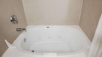 Una bañera estándar con panel de control de ducha, toallero y cortina de baño.