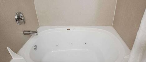 Eine Standardbadewanne mit Duschbedienelement, Handtuchhalter und Duschvorhang.